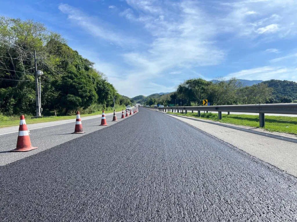 Equipe trabalhando na aplicacao de microrrevestimento asfaltico no pavimento da RJ-124, a Rodovia dos Lagos, que liga a Regiao Metropolitana a Regiao dos Lagos